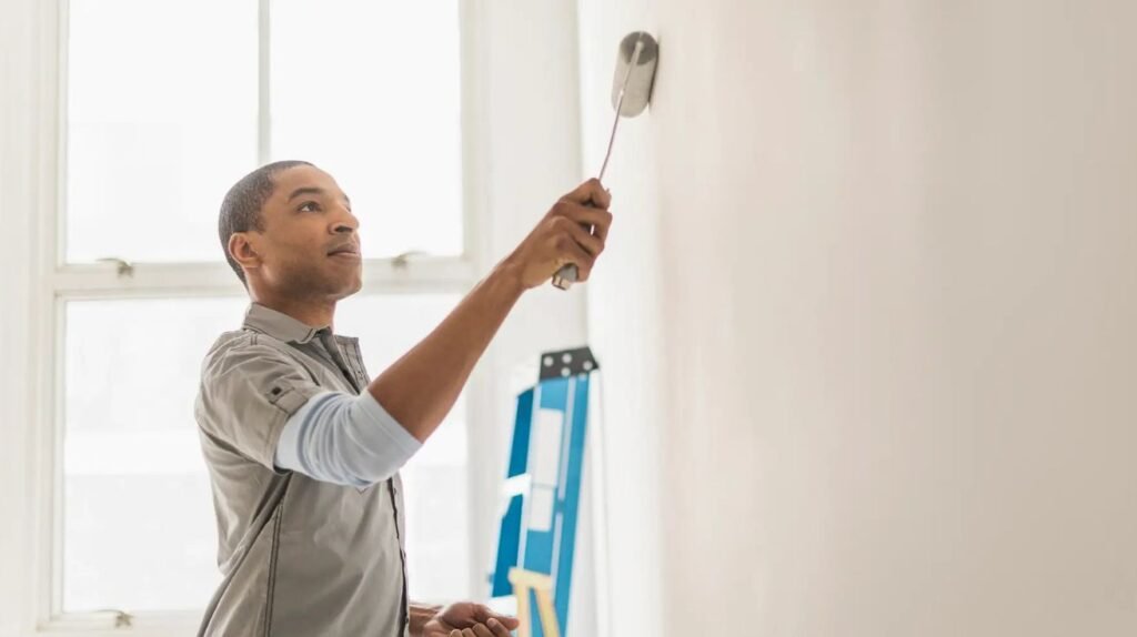 Professional interior house painter in Dubai applying matte finish on living room wall.
